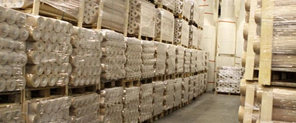 Stora lager av plastrullar på pallar i ett lagerlokal. Plastmaterial redo för leverans.