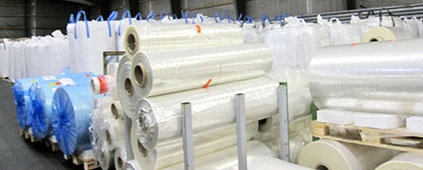 Stora rullar av transparent plastfilm i lagerlokal, redo för användning inom förpackning eller tillverkning. Materialinformation om plast och dess olika användningsområden.