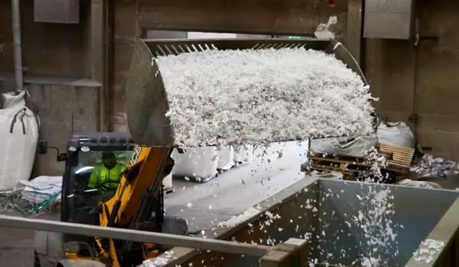 Frontlastare dumpar plastflingor i container